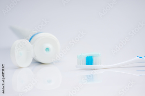 Toothbrush, toothpaste and water on a white background.
