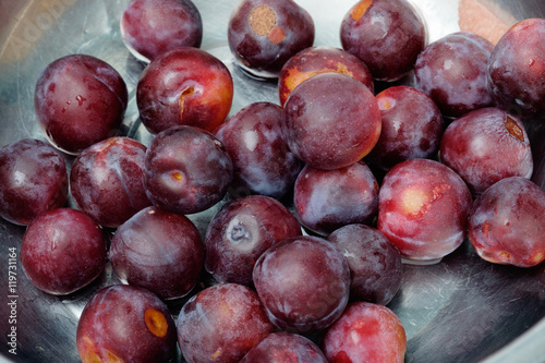 Ripe plums fruit in metal bowl