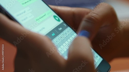 Young woman using smartphone while doing homework. Hispanic people and college education. Female student studying and texting with mobile telephone at home, typing text message on cell phone. Close-up