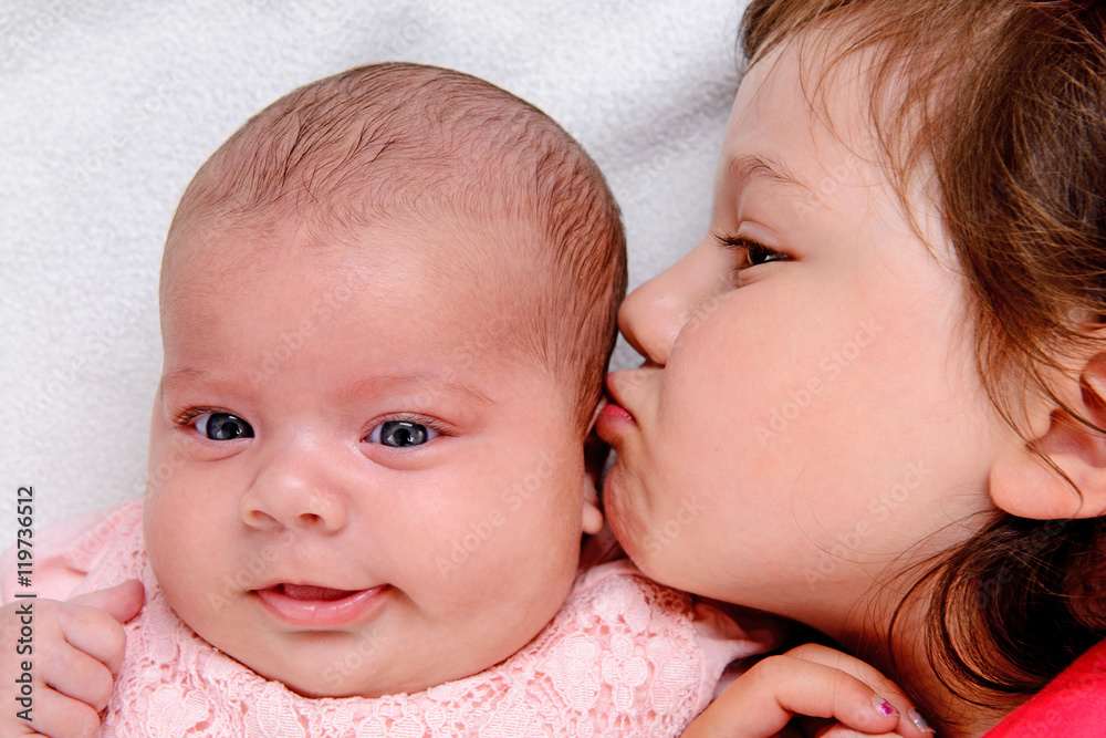 little girl kissing her baby- siste little girl kissing her baby- siste
