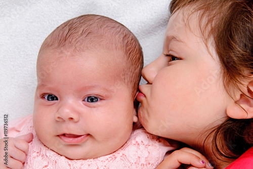 little girl kissing her baby- siste