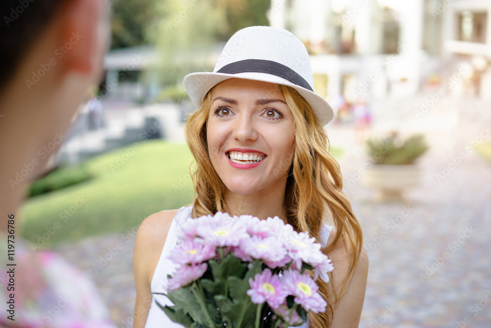 First date. Outdoor portrait of pretty young woman with flowers.