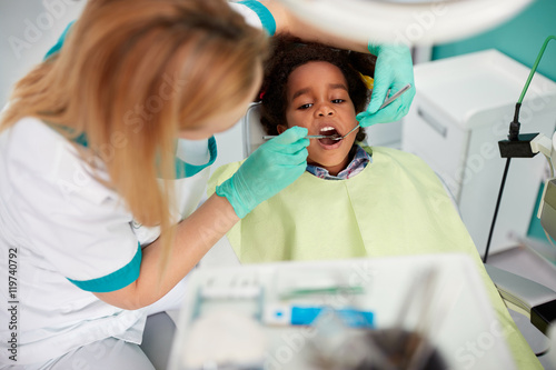 Female dentist repair tooth to nice black kid