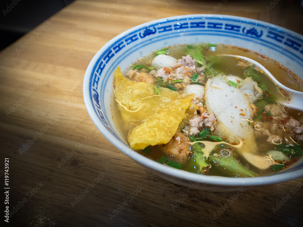 Spicy noodle  and Tom Yum  soup with red roast pork on wooden ta