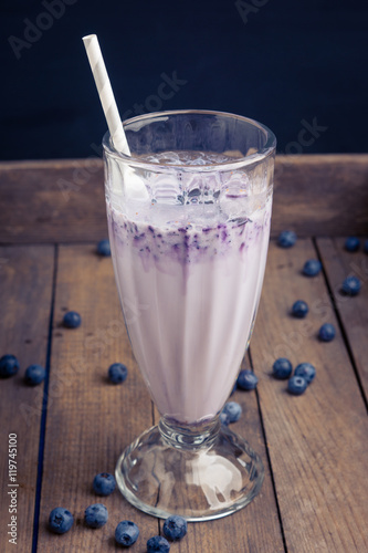 Blueberry milkshake on the wooden background. Toned image.