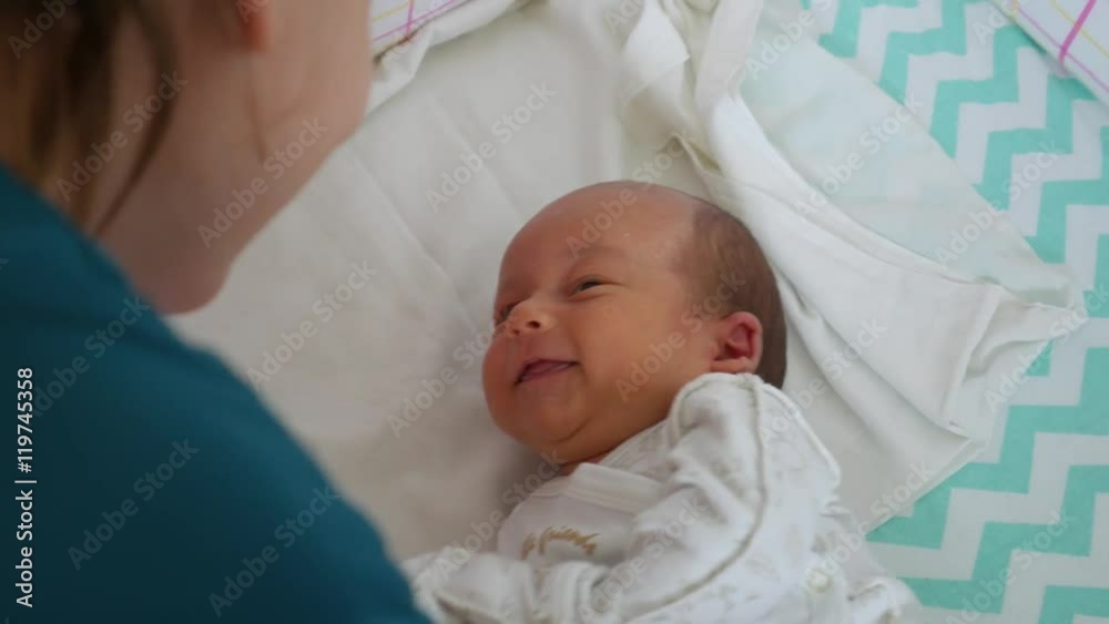 Active newborn baby looking at the mother and smiling to her Active newborn baby looking at the mother and smiling to her