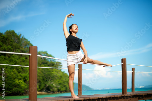 Asian girl doing Yoga pose at the pier