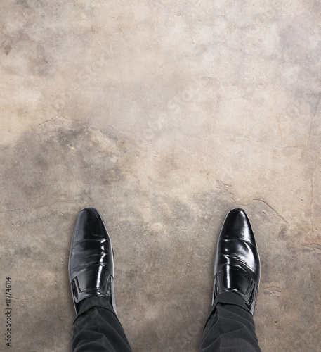 Business man standing at the beginning of a journey looking down at his feet