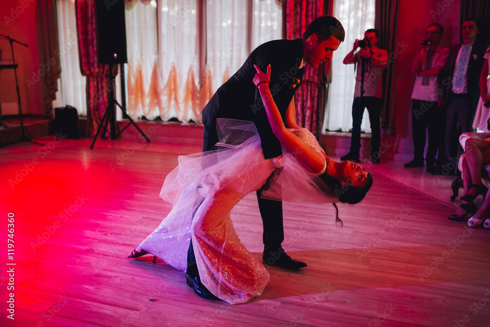 Fototapeta premium Happy bride and groom and their first dance, wedding in the elegant restaurant with a wonderful light and atmosphere