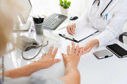 Close up of a medical examination.Middle aged woman with arthritis showing her hands to a female doctor. photo