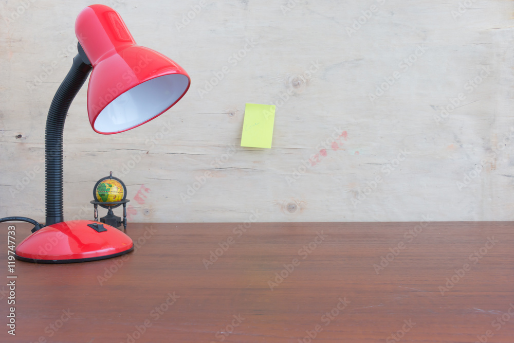 Metallic red lamp on the desk reading a book.