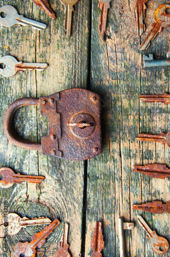 Old padlock and keys on wooden background from above