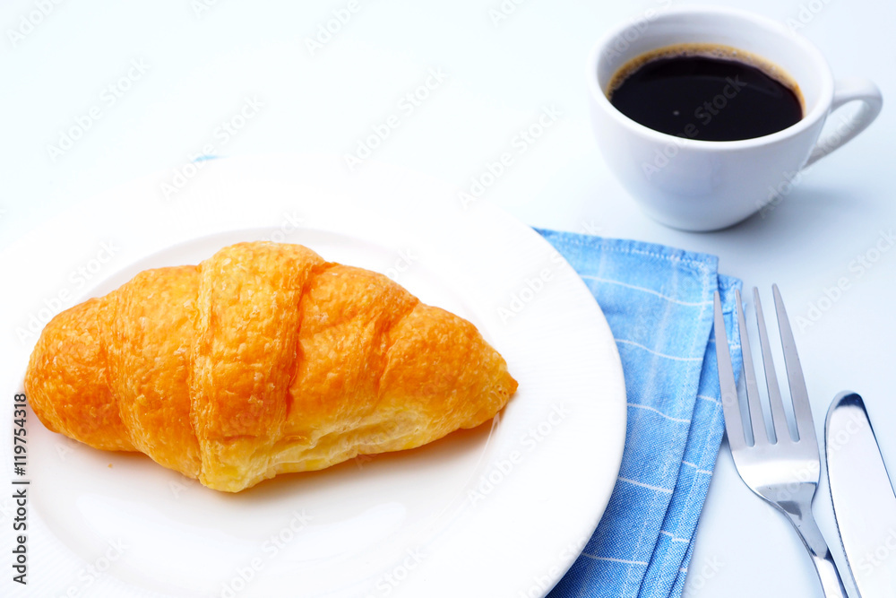 Close up of breakfast with croissants and a cup of black coffee.