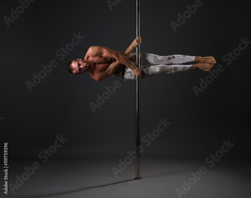 Studio image of male dancer exercising on pole