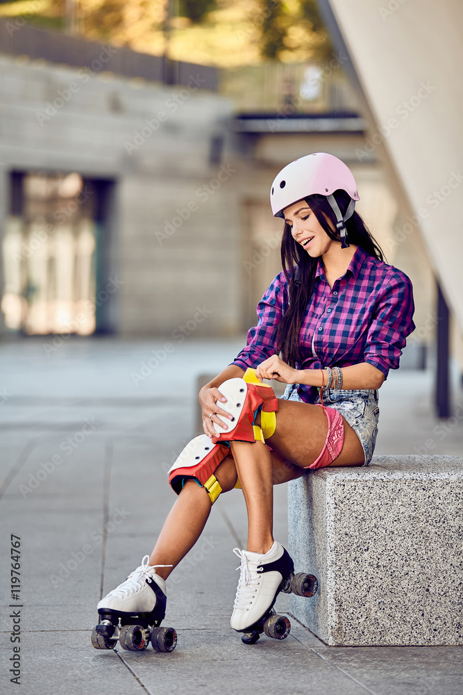 Active lifestyle girl is going to ride on roller skates. Stylish pink skating  helmet, knee pads and quad roller skate. Stock Photo | Adobe Stock