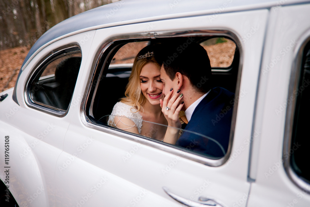 Happy wedding couple in white retro car