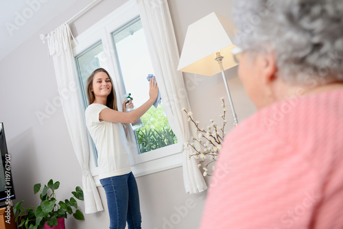 cheerful young girl helping with household chores elderly woman at home photo