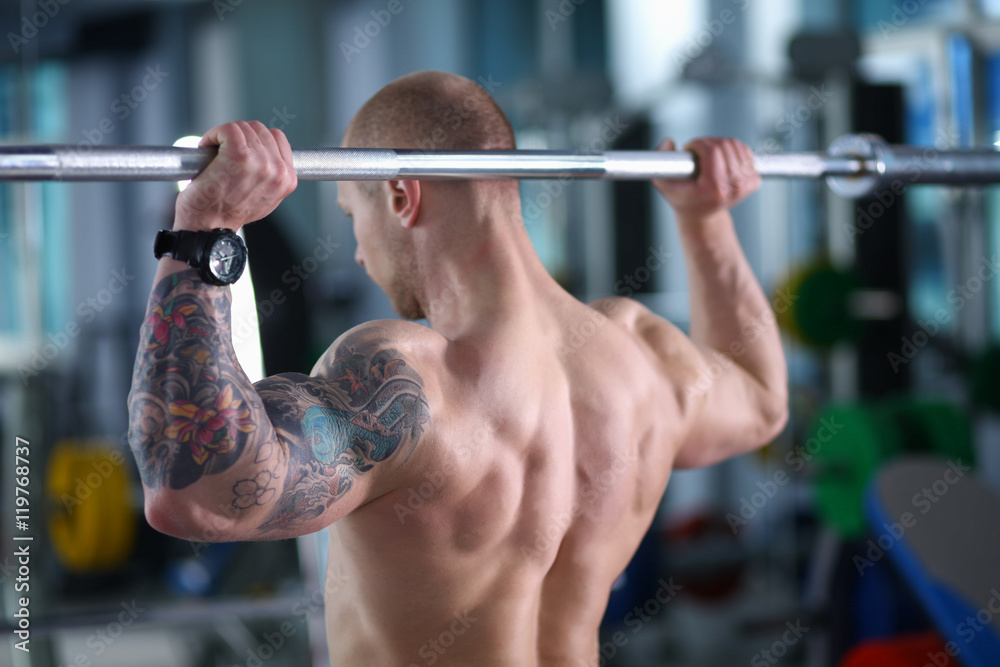 Fototapeta premium Young man lifting the barbell in gym with instructor