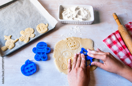 Making cookies for Halloween and Thanksgiving. Fun food for kids, a snack for a party. Woman cut out cookies using cookie cutters, hands in the frame