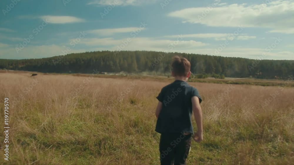 Little boy playing soccer in the field. Child running through meadow with a ball. Countryside and forest Little boy playing soccer in the field. Child running through meadow with a ball. Countryside and forest
