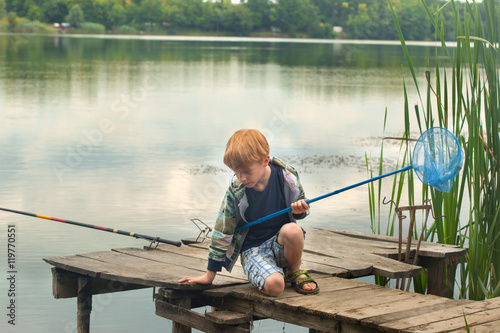 Red hair boy on the wooden dock with a fishing net