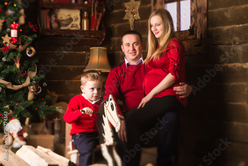 Young pregnant mother, father and small son celebrating Christmas at home