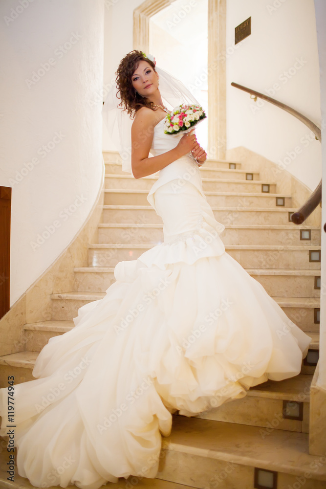 Cute brunette bride dressing for her wedding in the room Cute brunette bride dressing for her wedding in the room