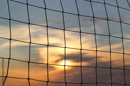 Old net for beach volleyball on sea coast on sunrise