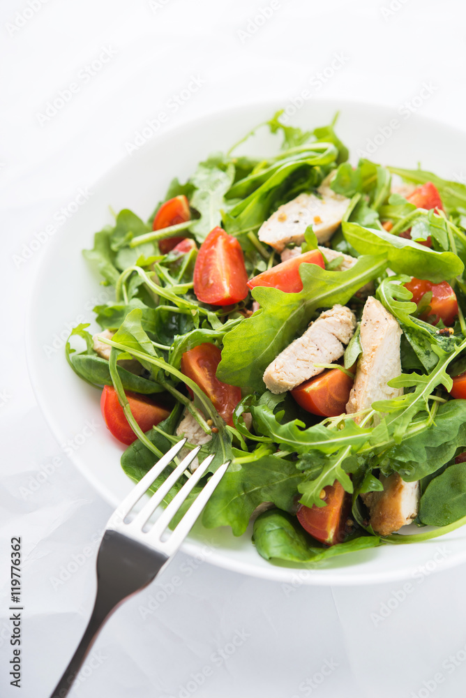 Fresh salad with chicken, tomato and greens (spinach, arugula) on white background close up. Healthy food.