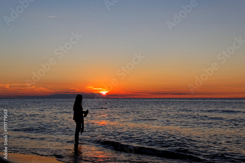 Nostalgic girl on the beach during sunset over the sea.