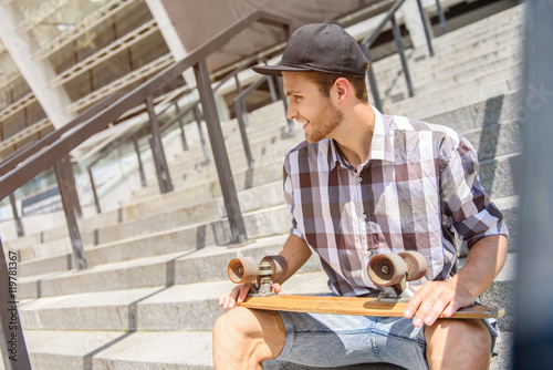 Cheerful male skater relaxing on staircase