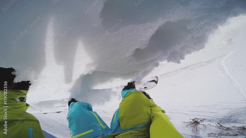 Snowboarder get up on top snowy mountain for backcountry ride. Sunny day. Go pro camera on head.