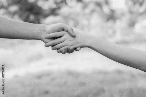 Close up on a man and a woman holding hands at green background,Hand help and hope concept,helping hand