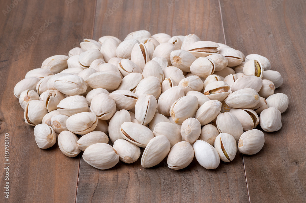 Roasted and salted pistachios in shell on wooden background