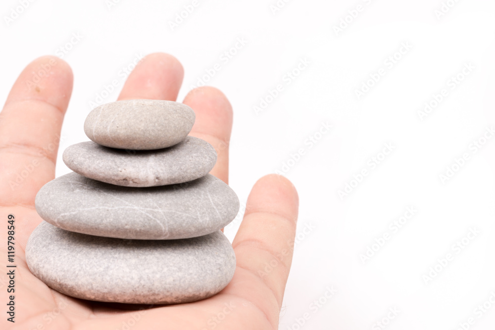Hand holding balanced grey stones over white background Hand holding balanced grey stones over white background