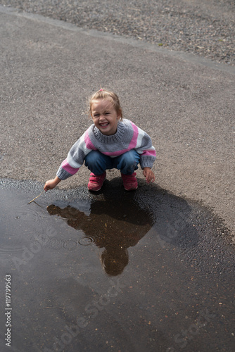 Little girl playing in a big puddle