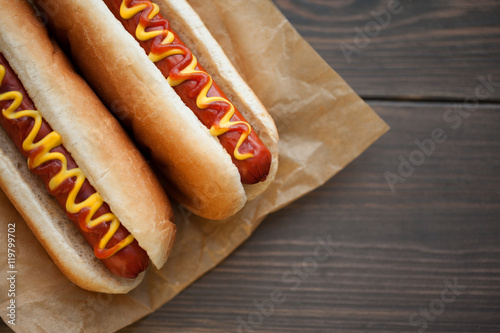 Barbecue Grilled Hot Dog with Yellow Mustard and ketchup on wooden table. Fast food. photo