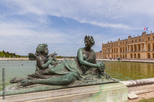 Sculptures with royal palace in background in Gardens of Versailles, Paris, France.