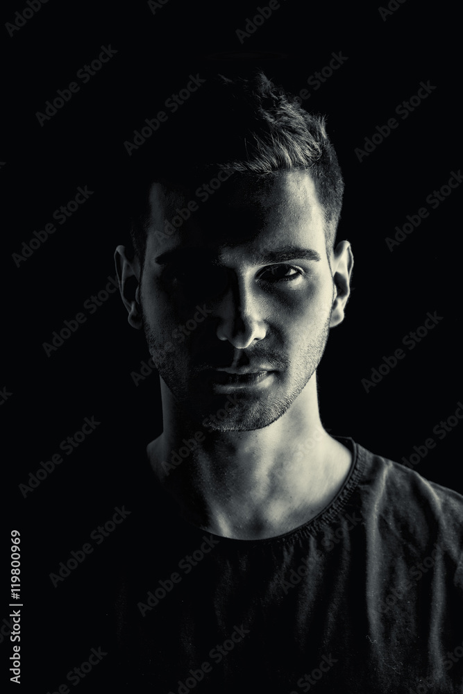 Handsome and stylish young man with black t-shirt. Black and white shot. Looking at camera.