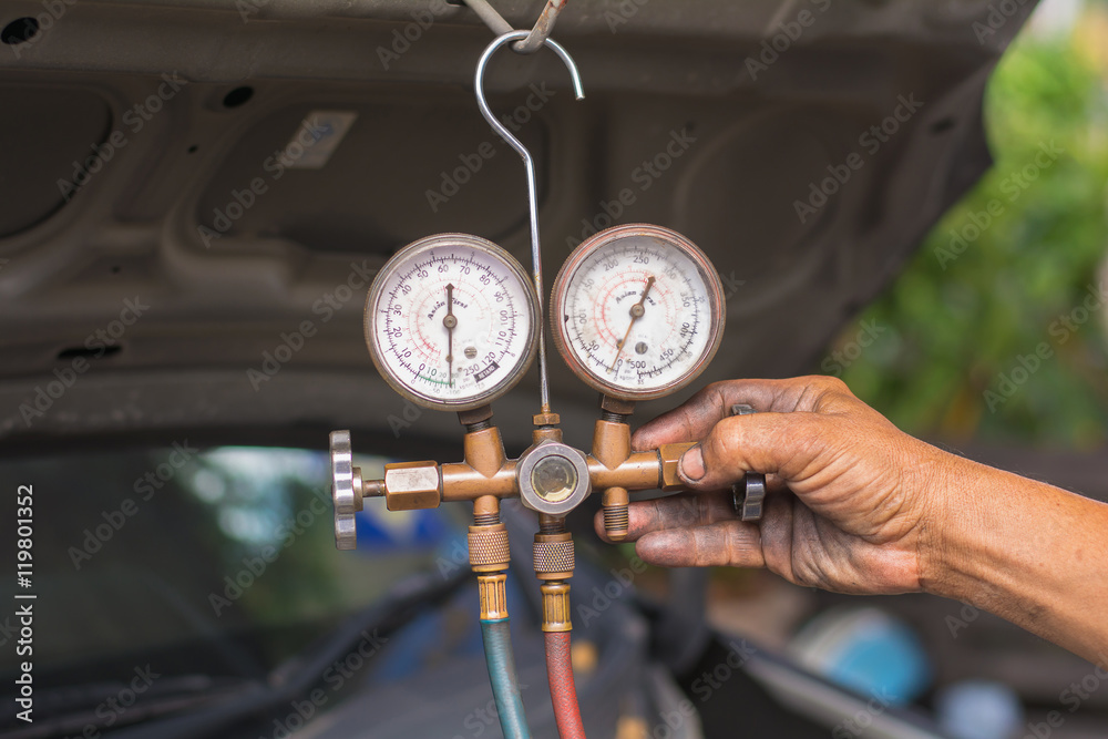 Fototapeta premium Dirty hands holding a manometers on equipment for filling air conditioners