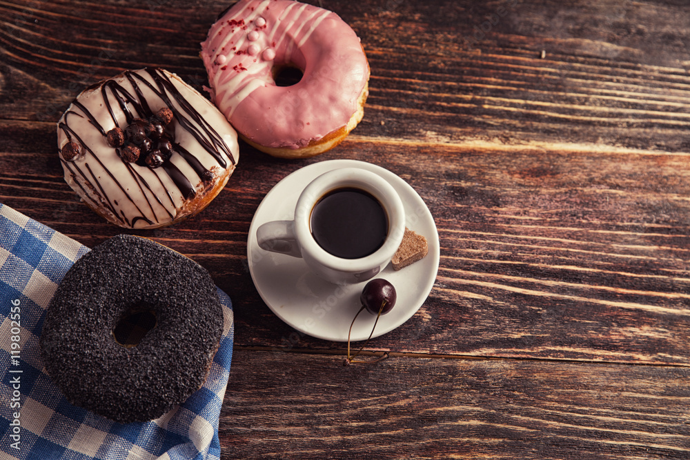 fresh donut with coffee on wooden table with napkin, spoon and c