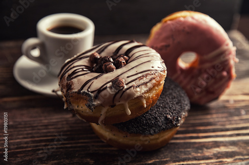fresh donut with coffee on wooden table with napkin, spoon and c