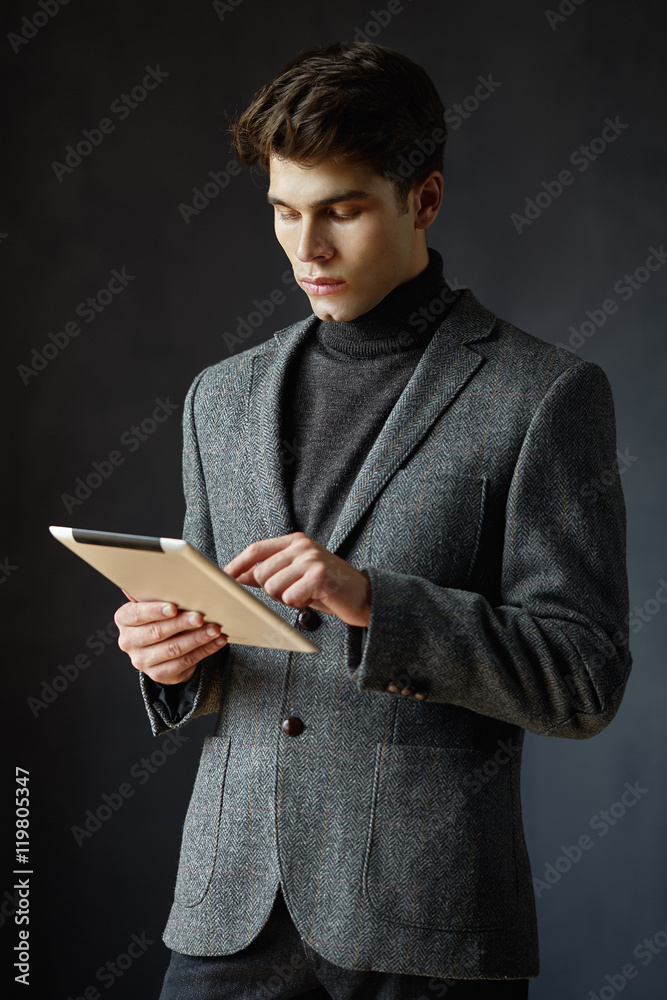 Guy with hairstyle holding tablet and working on it Guy with hairstyle holding tablet and working on it