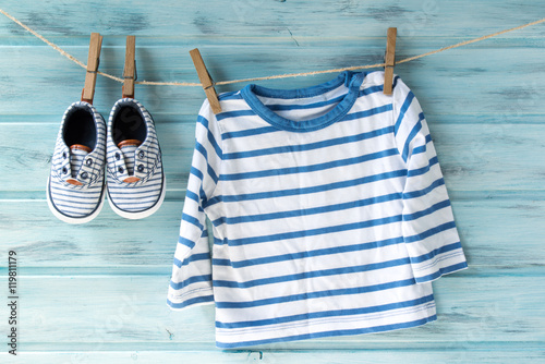 Baby boy striped shirt and baby shoes on a clothesline