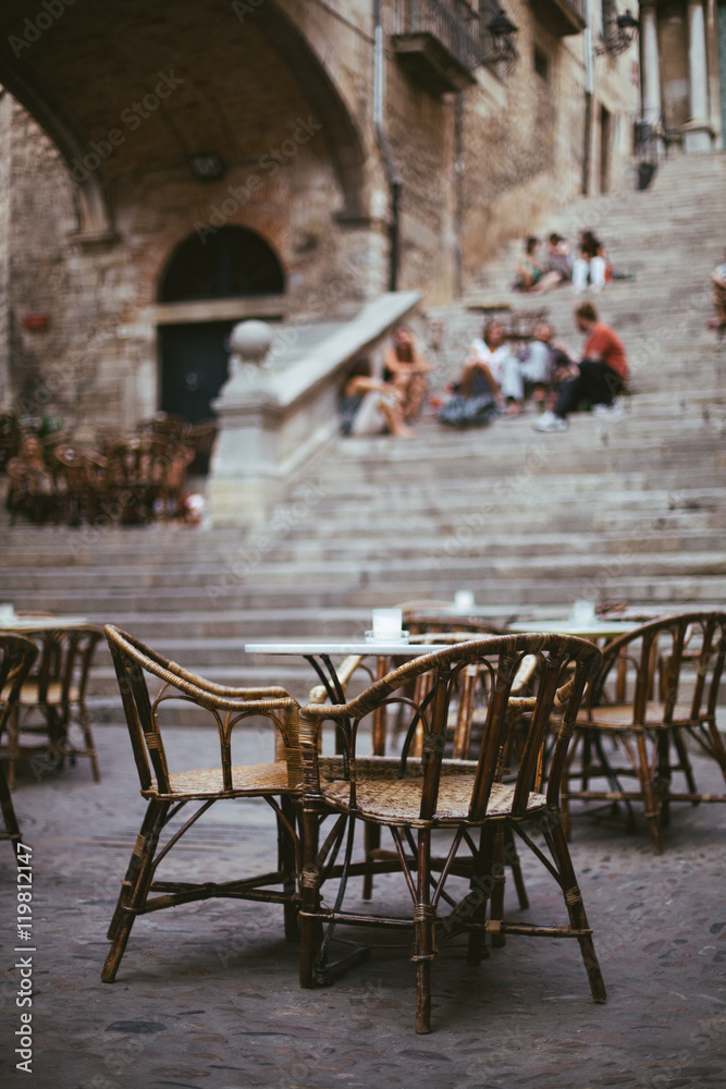 Empty outdoor cafe in old town. Street restaurant. Menu of Mediterranean tasty food. Evening daytime. Time for evening meal.  People sitting on the steps and talking