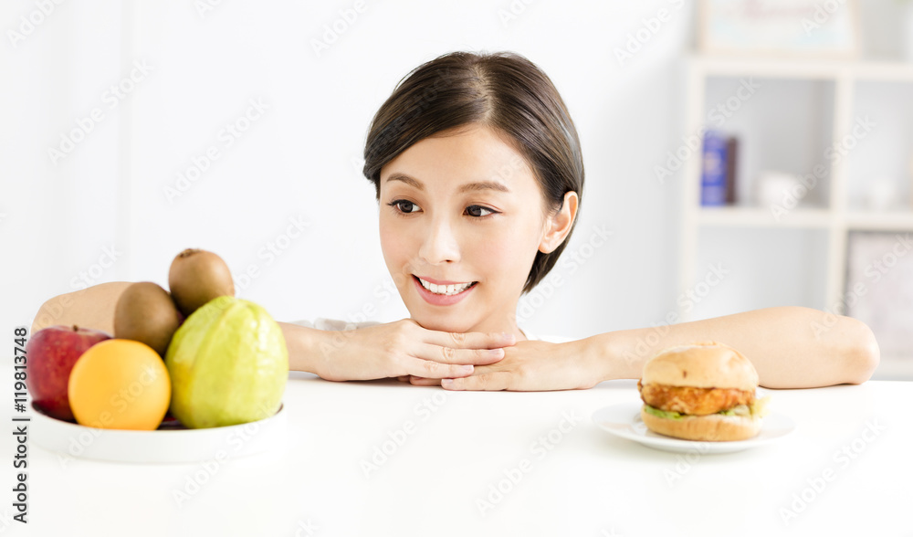 Young woman making choice between healthy and harmful food Young woman making choice between healthy and harmful food