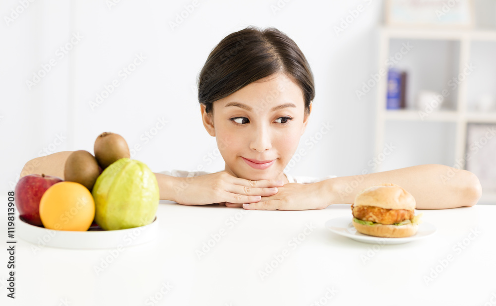 Young woman making choice between healthy and harmful food Young woman making choice between healthy and harmful food