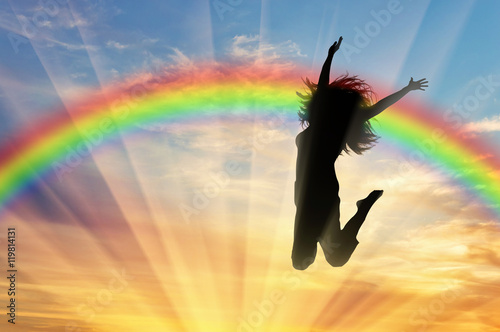 Happy woman jumping near rainbow photo