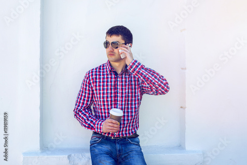 man in shirt and jeans glasses, talking on the phone, smartphone, the concept of summer, businessman vacation. City lifestyle. the street in the park.