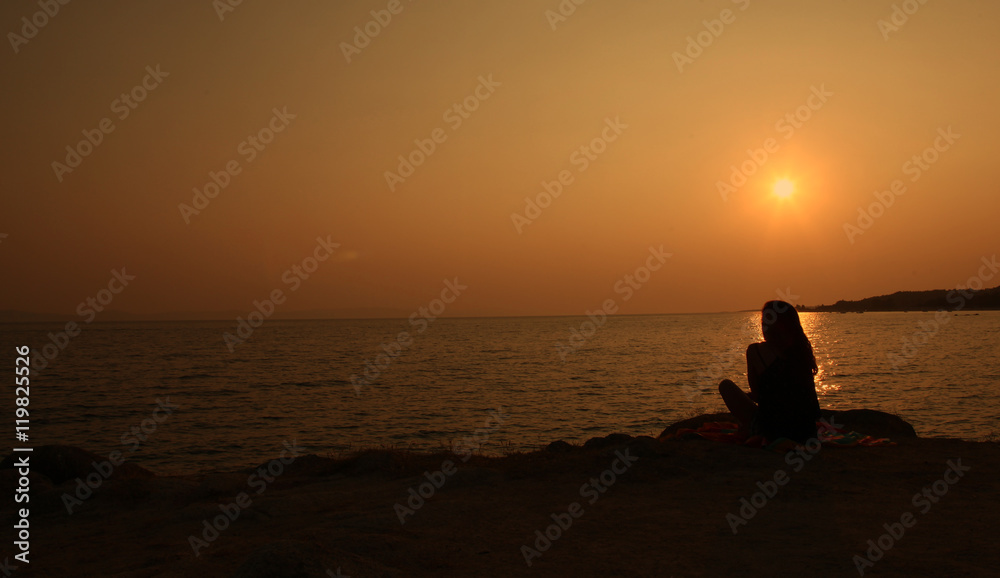 Girl is waiting on seaside during beautiful sunset
